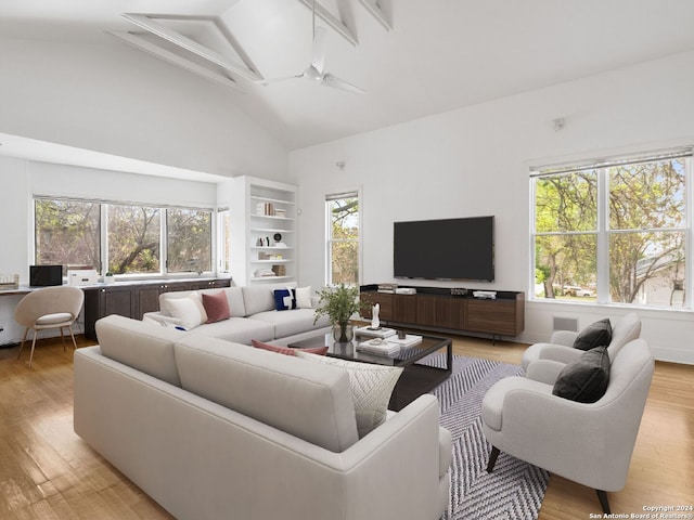 living room featuring beamed ceiling, light hardwood / wood-style floors, high vaulted ceiling, and a healthy amount of sunlight