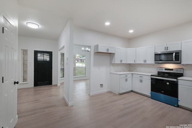 kitchen featuring appliances with stainless steel finishes, tasteful backsplash, white cabinets, light wood-type flooring, and a chandelier