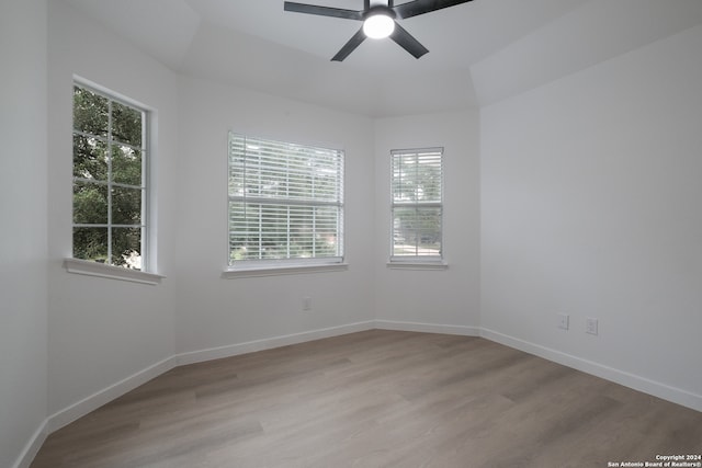 empty room featuring a healthy amount of sunlight, ceiling fan, and light hardwood / wood-style floors