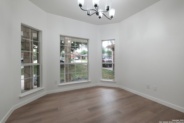 unfurnished room featuring an inviting chandelier and hardwood / wood-style flooring