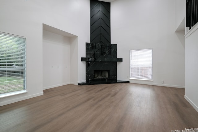 unfurnished living room featuring wood-type flooring, a high ceiling, and a fireplace