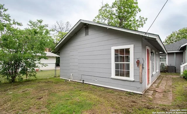 view of property exterior with central AC and a lawn