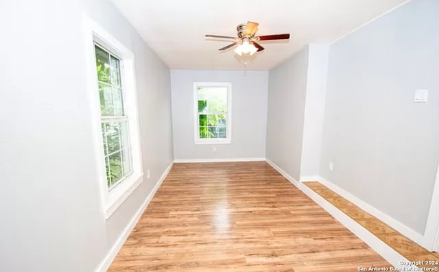 empty room with ceiling fan, light wood-type flooring, and a wealth of natural light