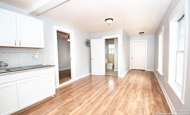 kitchen with a healthy amount of sunlight, light hardwood / wood-style flooring, tasteful backsplash, and white cabinetry