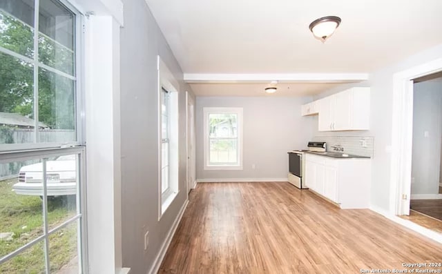 kitchen with backsplash, stove, white cabinets, and light wood-type flooring