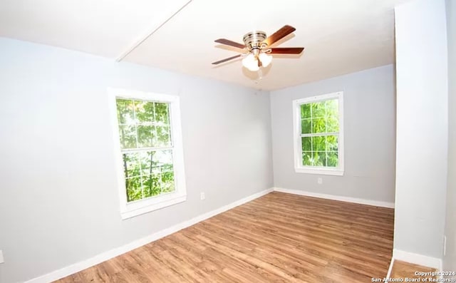 empty room featuring a wealth of natural light, ceiling fan, and hardwood / wood-style flooring