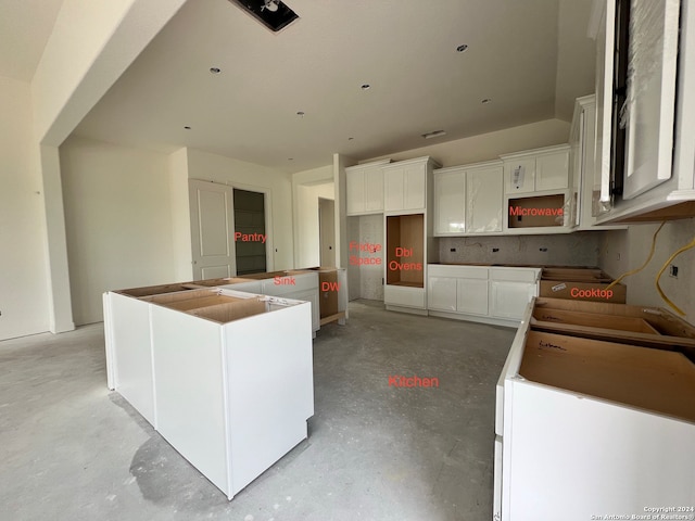 kitchen with concrete floors, a center island, and white cabinetry