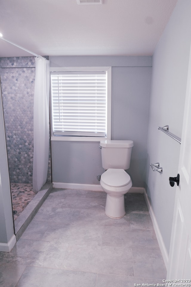 bathroom featuring walk in shower, toilet, and tile floors