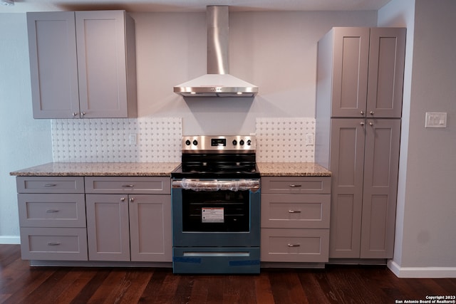 kitchen featuring light stone countertops, gray cabinets, dark hardwood / wood-style flooring, wall chimney range hood, and stainless steel electric range oven