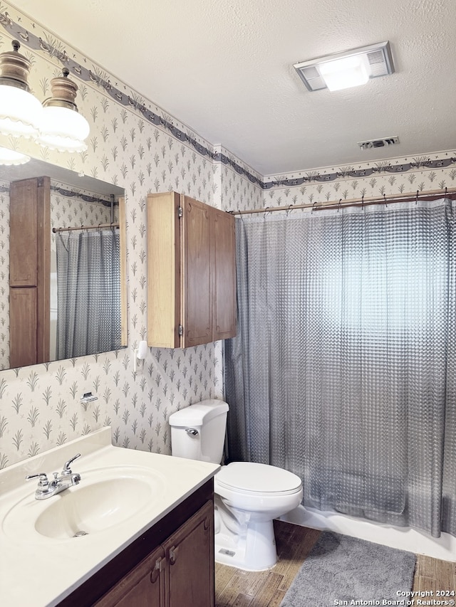 bathroom featuring hardwood / wood-style floors, vanity, toilet, and a textured ceiling