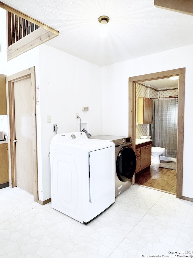 laundry area with washing machine and dryer, hookup for a washing machine, and light tile floors