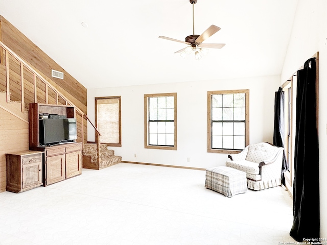 living room with ceiling fan and wooden walls