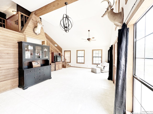 living room featuring ceiling fan with notable chandelier, wood walls, and high vaulted ceiling