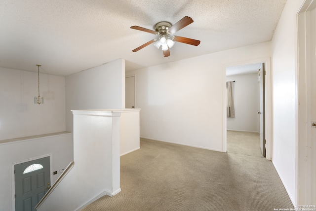 hall featuring light carpet and a textured ceiling