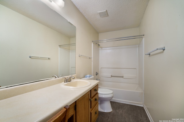 full bathroom with a textured ceiling, vanity, hardwood / wood-style floors, toilet, and  shower combination