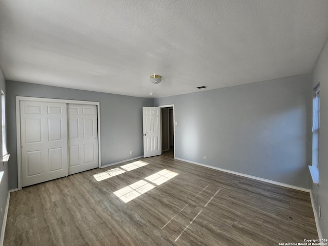 unfurnished bedroom featuring hardwood / wood-style flooring, a textured ceiling, and a closet