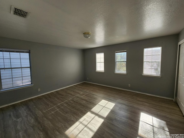 unfurnished room with dark hardwood / wood-style flooring and a textured ceiling