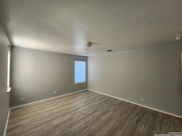 unfurnished room featuring hardwood / wood-style floors, plenty of natural light, and a textured ceiling