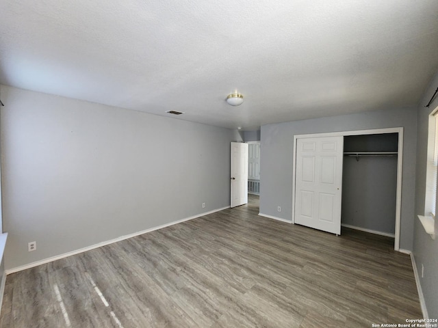 unfurnished bedroom with a closet, dark wood-type flooring, and a textured ceiling