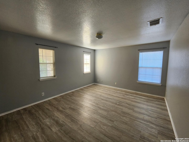 spare room featuring hardwood / wood-style floors and a textured ceiling