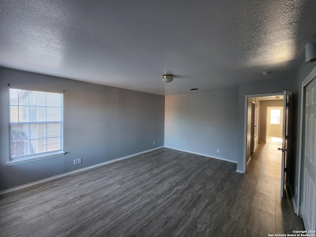 spare room featuring a textured ceiling and dark wood-type flooring