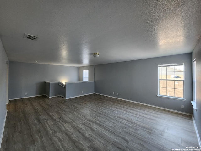 unfurnished room featuring a textured ceiling and dark hardwood / wood-style floors