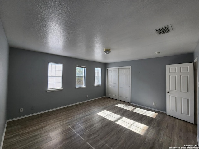 unfurnished bedroom with dark hardwood / wood-style floors, a textured ceiling, and a closet