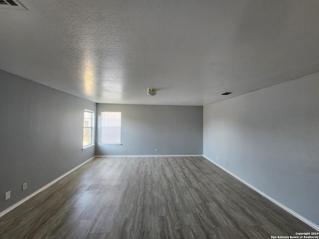 unfurnished room featuring a textured ceiling and dark wood-type flooring