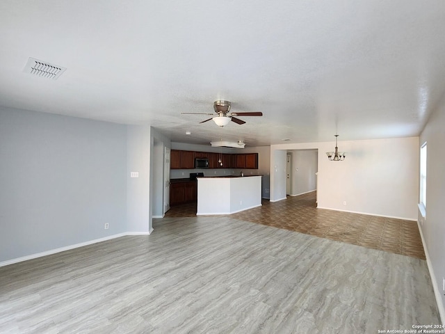 unfurnished living room featuring light hardwood / wood-style floors and ceiling fan with notable chandelier