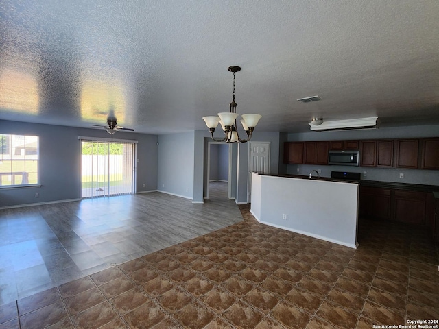 kitchen featuring stove, ceiling fan with notable chandelier, decorative light fixtures, and a textured ceiling