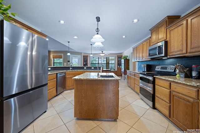 kitchen with appliances with stainless steel finishes, plenty of natural light, a kitchen island with sink, and tasteful backsplash