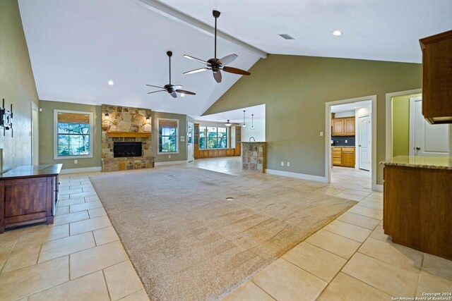 living room featuring ceiling fan, beam ceiling, light tile patterned flooring, and a stone fireplace