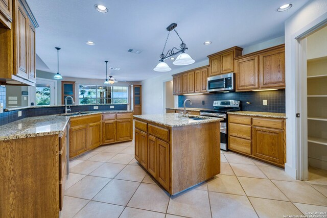 kitchen with sink, decorative light fixtures, appliances with stainless steel finishes, an island with sink, and kitchen peninsula