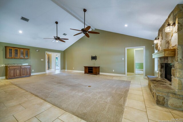 unfurnished living room with a fireplace, high vaulted ceiling, ceiling fan, and light tile patterned floors