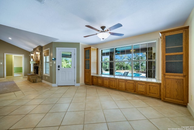 tiled entrance foyer featuring ceiling fan, a fireplace, and vaulted ceiling