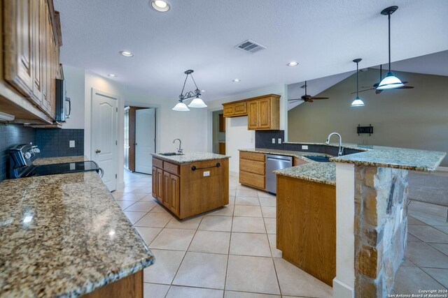 kitchen featuring backsplash, hanging light fixtures, appliances with stainless steel finishes, sink, and a center island with sink