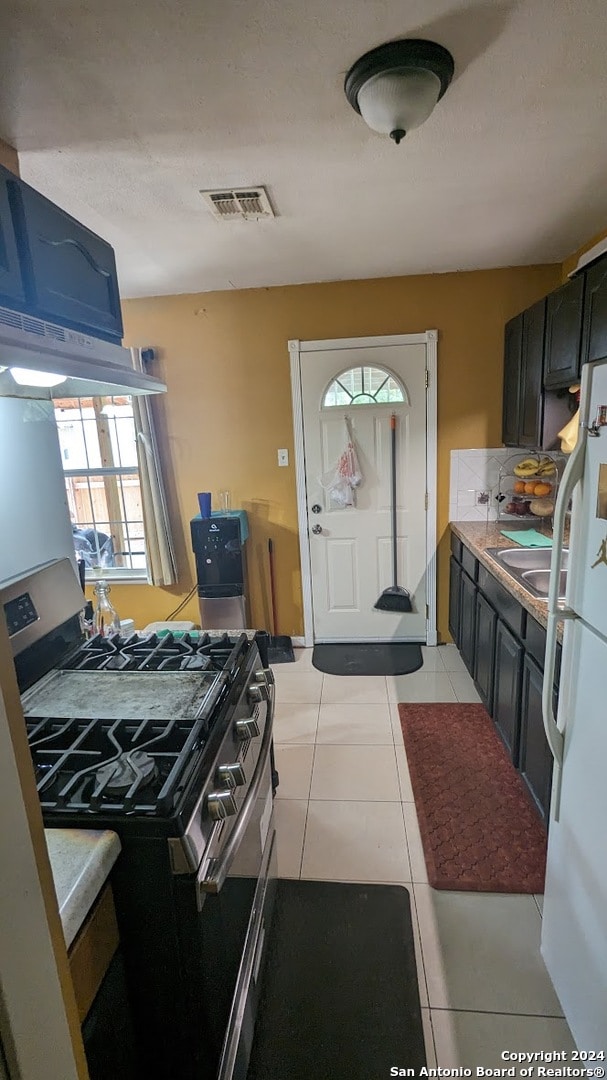 kitchen with blue cabinetry, white refrigerator, light tile floors, and range with two ovens