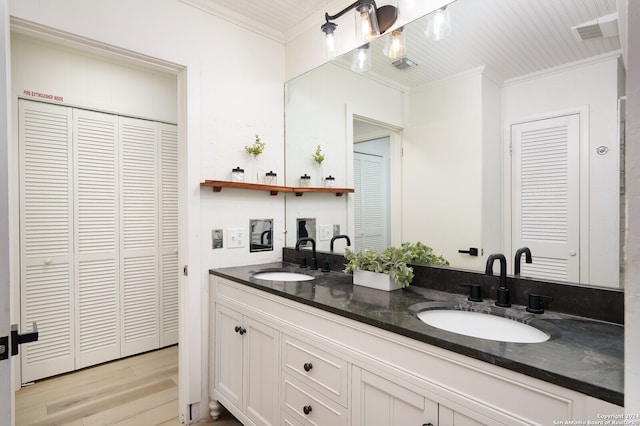 bathroom with hardwood / wood-style flooring, dual bowl vanity, and crown molding