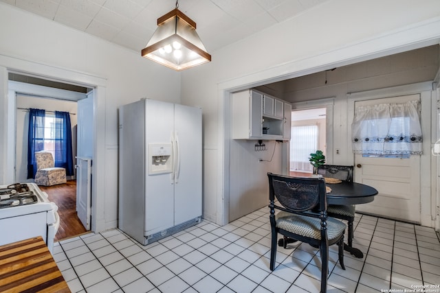 kitchen with hanging light fixtures, white appliances, and light tile floors