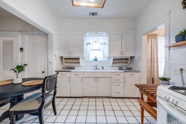 kitchen featuring tasteful backsplash, white cabinetry, and light tile floors