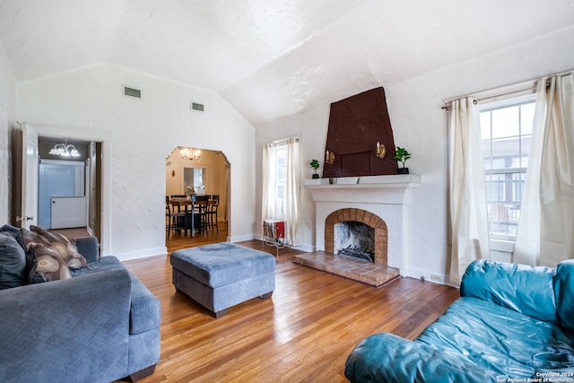 living room with lofted ceiling, hardwood / wood-style floors, and a brick fireplace