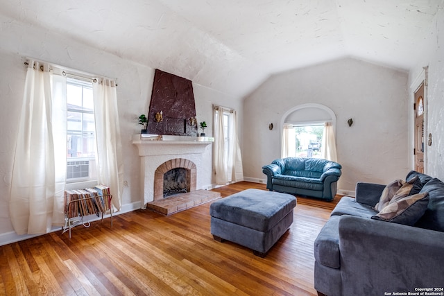 living room featuring wood-type flooring, lofted ceiling, and a fireplace