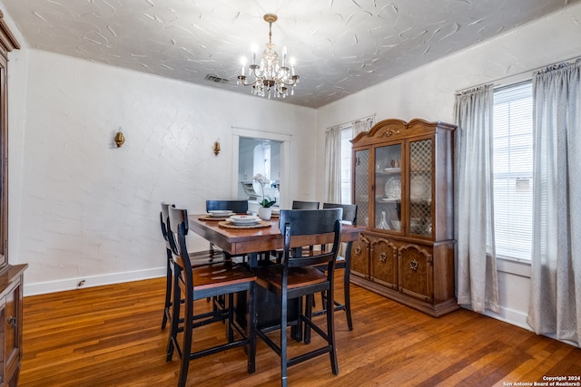 dining space featuring hardwood / wood-style flooring and a chandelier