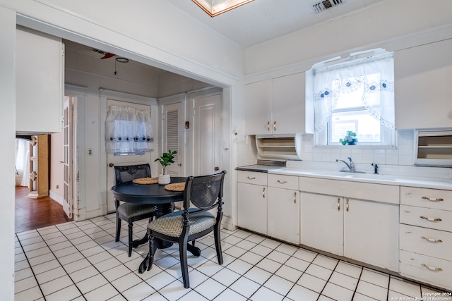 kitchen with backsplash, sink, light wood-type flooring, and white cabinetry