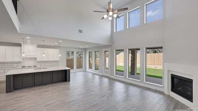 interior space featuring a center island with sink, a high ceiling, white cabinetry, and ceiling fan