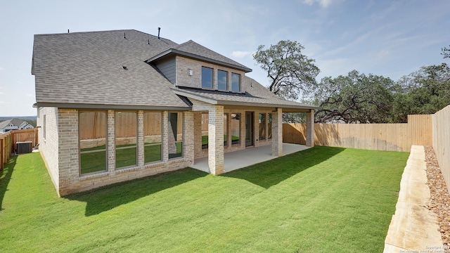 rear view of house with cooling unit, a lawn, and a patio