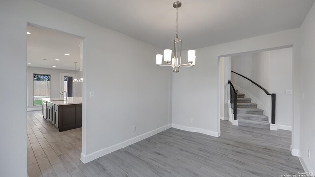 unfurnished dining area featuring light hardwood / wood-style flooring, an inviting chandelier, and sink