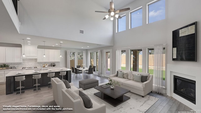 living room featuring a high ceiling, light hardwood / wood-style floors, and ceiling fan