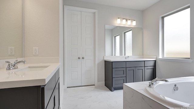 bathroom featuring a relaxing tiled tub and vanity