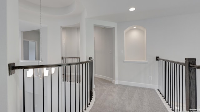 corridor featuring light colored carpet and an inviting chandelier